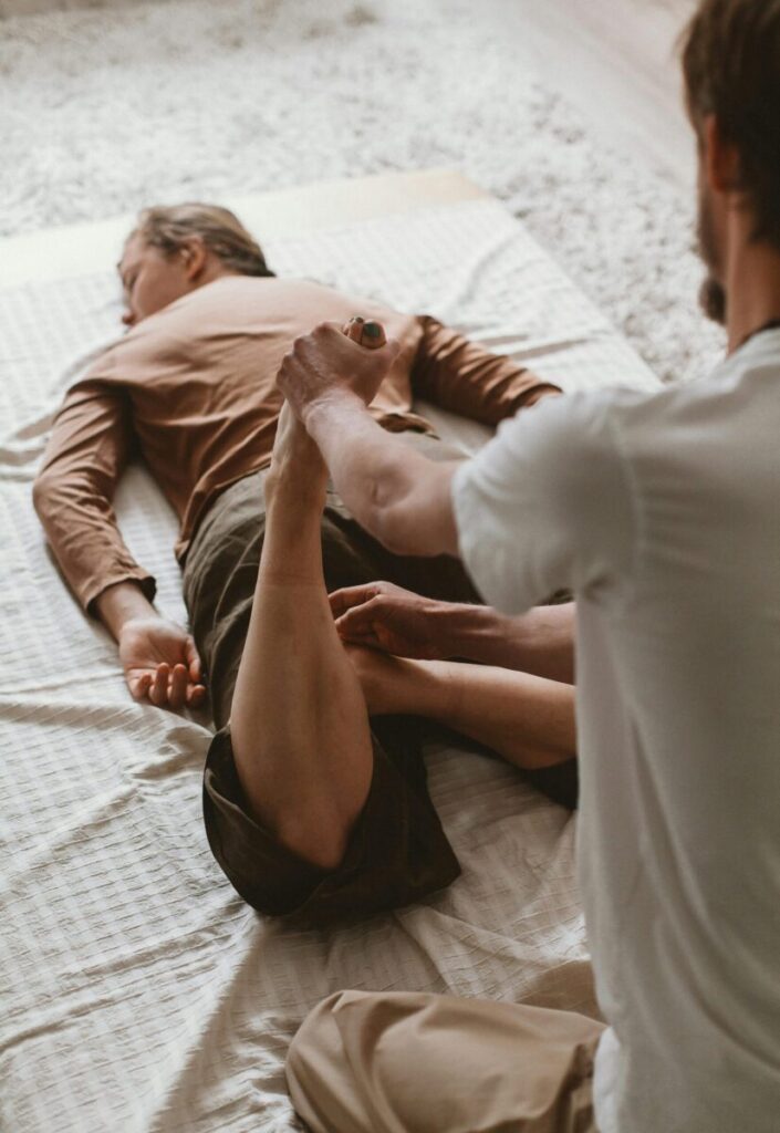 Therapist helps client stretch during a physiotherapy session indoors.